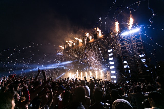 concert with lots of people partying and streamers in the sky. They are all having fun