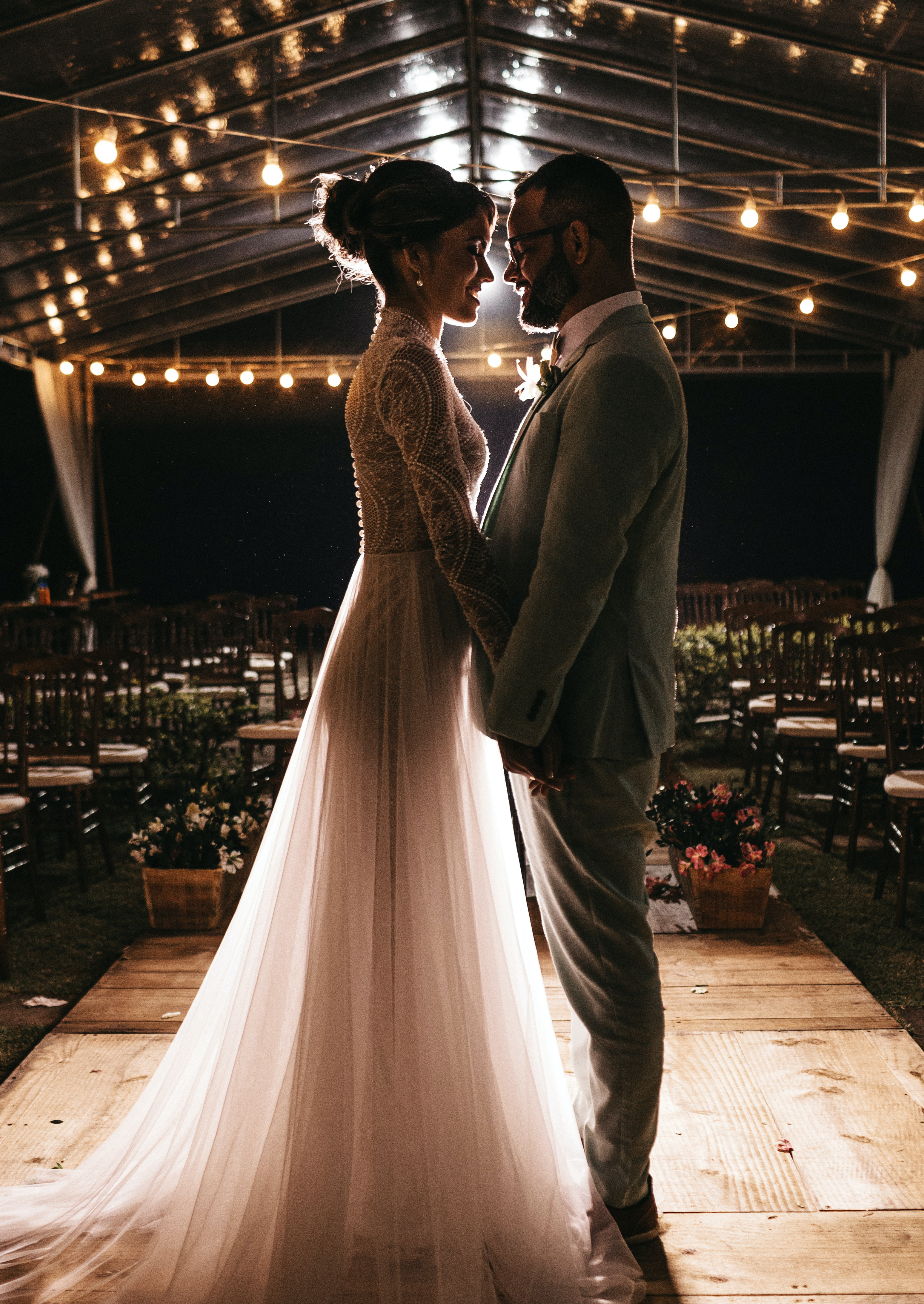bride and groom holding hands on podium with lights on the ceiling